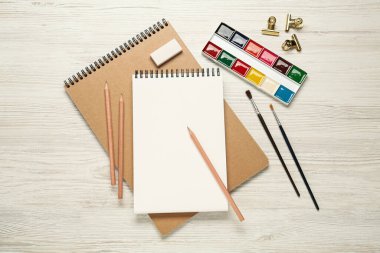 Düz kompozisyon ve beyaz ahşap masa üzerinde boş çizim defteri