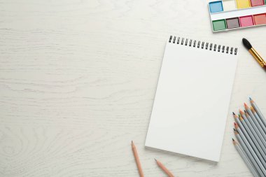 Düz kompozisyon ve beyaz ahşap masa üzerinde boş çizim defteri. Metin için boşluk