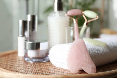 Rose Quartz gua sha aracı, doğal yüz silindirleri ve hasır masa içerisindeki tuvalet malzemeleri. Metin için boşluk
