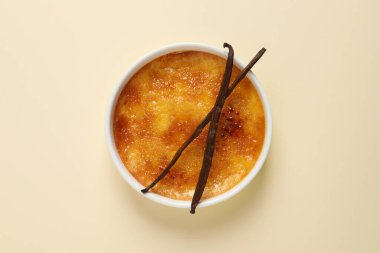 Bej arka planda vanilya çubuklu leziz creme brulee, üst manzara