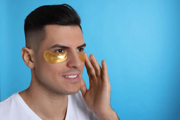 Man Applying Golden Eye Patch Light Blue Background Space Text — Stock Photo, Image