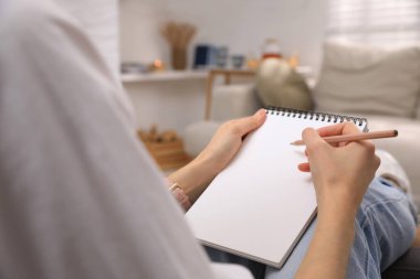 Çizim defterinde kalemle çizen kadın, yakın plan.