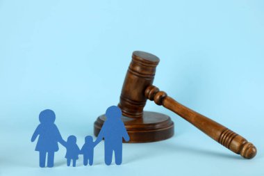 Kağıt aile figürü ve açık mavi arka planda ahşap tokmak. Çocuk evlat edinme kavramı