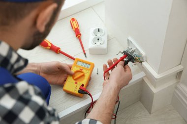 Elektrikçi ve testçi içeride voltajı kontrol ediyor, yakın plan.