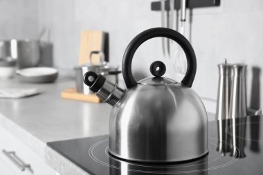 Stainless steel kettle on electric stove in kitchen clipart