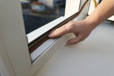 İnşaat işçisi pencereye köpük bandı yapıştırıyor, kapatıyor.
