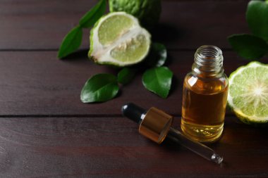 Bir şişe temel yağ, pipet ve ahşap masada taze bergamot meyvesi. Metin için boşluk