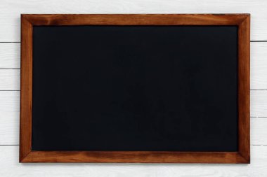 Beyaz ahşap duvarda asılı temiz siyah karatahta