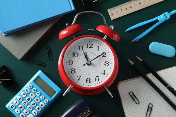 目覚まし時計と緑の背景に異なる文房具とフラットレイアウト組成 学校の時間 — ストック写真