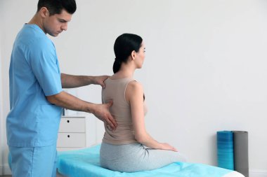 Ortopedist klinikte kadının sırtını muayene ediyor, mesaj için yer var. Skolyoz tedavisi