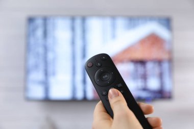 Uzaktan kumandalı bir kadın evde televizyon seyrediyor, kapatıyor. Metin için boşluk