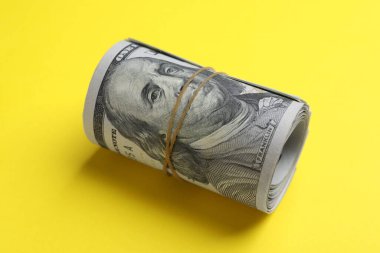 Sarı arka planda yuvarlanmış dolar banknotları, yakın plan. Amerikan ulusal para birimi