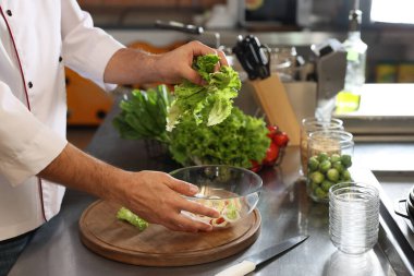 Restoran mutfağında salata yapan profesyonel şef, yakın plan.
