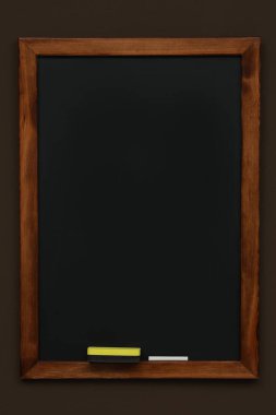 Kahverengi duvarda asılı temiz siyah karatahta