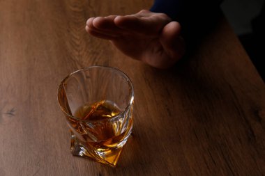 Ahşap masada viski içmeyi reddeden adam, yakın plan. Alkol bağımlılığı tedavisi