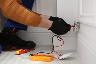 Elektrikçi ve testçi içeride voltajı kontrol ediyor, yakın plan.