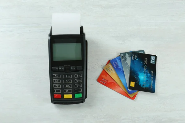 新的现代化支付终端和白色木制桌子上的信用卡 — 图库照片