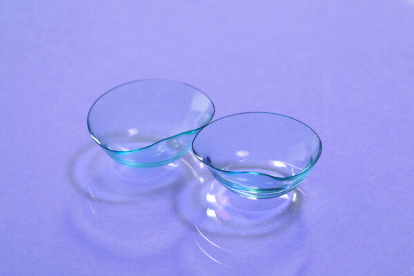 Pair of contact lenses on violet background