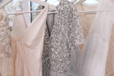 Atölyede farklı güzel elbiseli askılar, yakın plan.