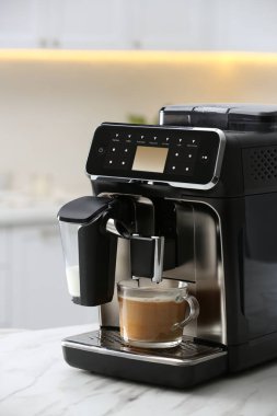 Modern espresso makinesi ve mutfakta beyaz mermer tezgahta sütlü cam kahve.