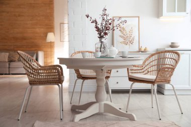 Yemek odasının içinde yuvarlak masa ve hasır sandalyeler var.