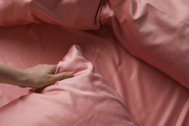 Güzel pembe ipek çarşaflarla yatağı yapan kadın, yakın çekim manzarası