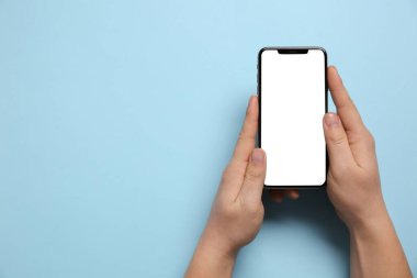 Açık mavi arka planda akıllı telefonu olan bir kadın. Metin için boşluk