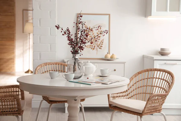 Dining room interior with tea set on round table and wicker chairs