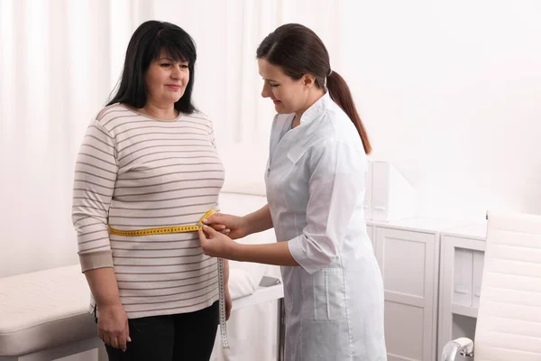 Klinikte Kilolu Bir Kadının Belini Bantla Ölçen Beslenme Uzmanı — Stok fotoğraf