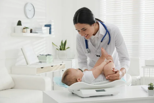 年轻儿科医生在诊所称可爱的小宝宝的重量 — 图库照片