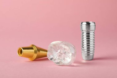 Pembe arka planda diş implantı parçaları, yakın plan.