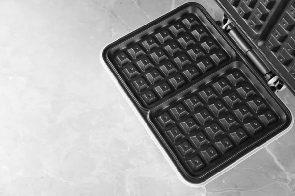 Gri masadaki elektrikli waffle makinesini aç. Metin için boşluk