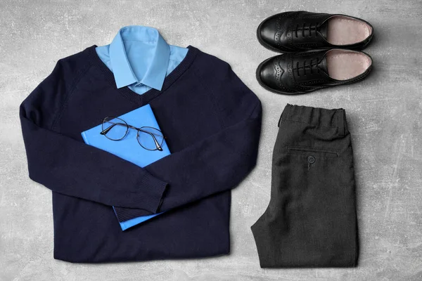 グレーの背景に男の子 眼鏡やノートブックのためのスタイリッシュな学校の制服 フラットレイ — ストック写真
