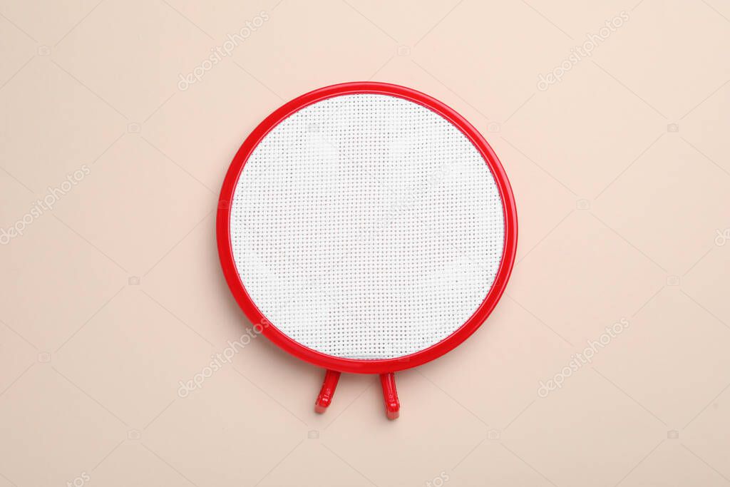 Embroidery hoop with fabric on beige background, top view