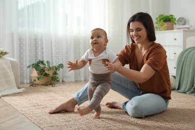 Anne, kızına evde yürümeyi öğrenirken bakıyor.