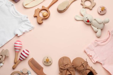 Açık pembe arka planda bebek kıyafetleri ve aksesuarları, düz yatış. Metin için boşluk