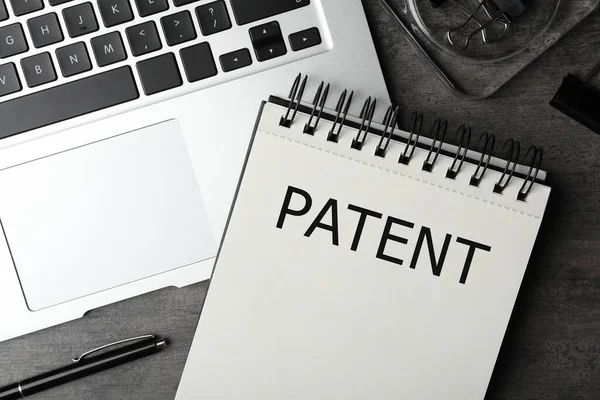 带有Patent和笔记本电脑的笔记本 放在灰色桌子上 — 图库照片