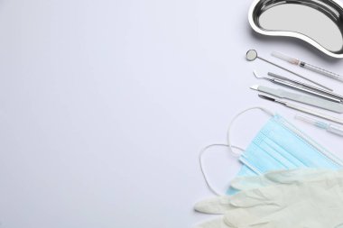 Farklı dişçi aletleri, yüz maskeleri ve arka planda eldivenler, düz yatış. Metin için boşluk