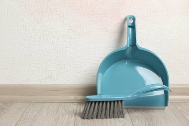 Kapalı alandaki ışık duvarının yanında faraşlı plastik süpürge. Metin için boşluk