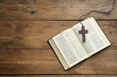 MYKOLAIV, UKRAINE - 20 ARALIK 2021: Ahşap masa üzerinde Hristiyan haçı ve İncil, üst manzara. Metin için boşluk