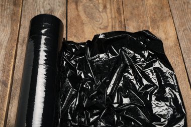 Tahta masanın üzerinde plastik gerilmiş film rulosu, yakın plan.