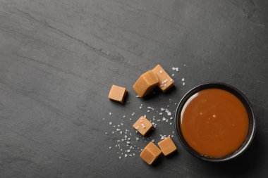 Lezzetli tuzlu karamel kasede ve siyah masada şekerleme, düz yerde. Metin için boşluk