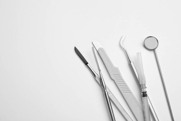 Set of different dentist's tools and syringe on light background, flat lay. Space for text