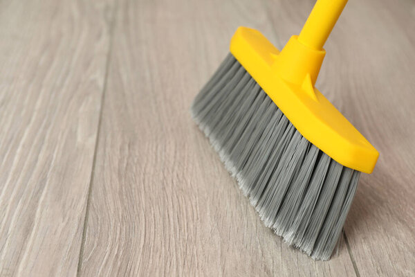 Sweeping wooden floor with plastic broom, closeup. Space for text