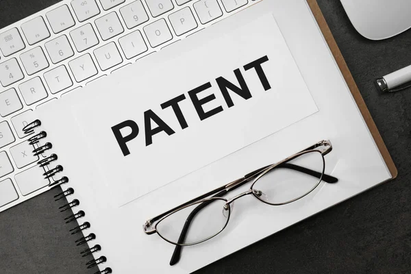 印有Patent字样的笔记本 键盘和眼镜放在黑桌上 — 图库照片