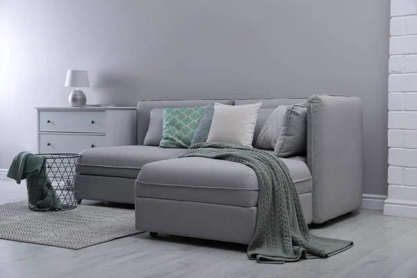 大きな灰色のソファと部屋の光の壁の近くの引き出しの胸 インテリアデザイン — ストック写真