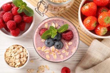 Lezzetli yulaf ezmeli smoothie ve beyaz ahşap masada böğürtlenli düz kompozisyon.