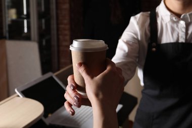Barista, kahveli paket kâğıt bardağı müşteriye veriyor, yakın plan.