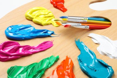 Beyaz arka planda boya ve fırçalı palet, yakın plan. Sanatçı ekipmanı