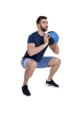 Atletik adam beyaza izole edilmiş ilaç topuyla çömelme yapıyor.